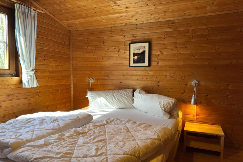 Gezellige houten slaapkamer in 'Type C House 363 364 361 362' Duitsland met dubbel bed en nachtkastje.