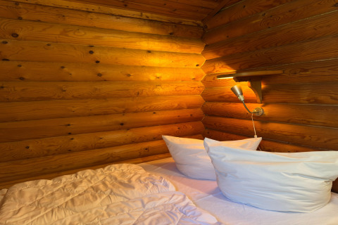 Knusse slaapkamer met witte kussens, houten wanden en lamp in Type C House 363 364 361 362 in Duitsland.