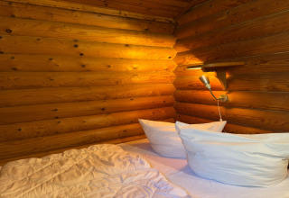 Knusse slaapkamer met witte kussens, houten wanden en lamp in Type C House 363 364 361 362 in Duitsland.