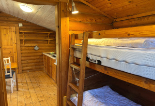 Cozy wooden lodge interior in Germany featuring bunk beds, a cabin kitchen, and dining table at Type C House 363 364 361 362.