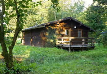 Casetta in legno 'Type C House 363 364 361 362', immersa nel verde tra erba e alberi, situata in Germania.
