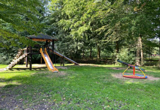 Speeltuin bij 'Type C House 363 364 361 362' in Duitsland, met glijbaan, klimrek en draaimolen in het groen.