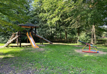 Aire de jeux près du «Type C House 363 364 361 362» en Allemagne avec toboggan, structure et manège en nature.