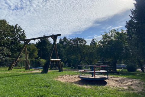 Playground with swings and a roundabout in green surroundings near Type C House 363 364 361 362, Germany.