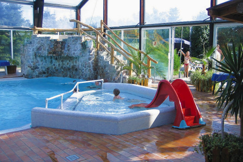 Indoor pool area at Type C House 363 364 361 362 in Germany, featuring a slide and stone waterfall.