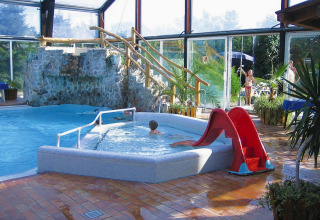 Binnenzwembadruimte bij Type C House 363 364 361 362 in Duitsland, met glijbaan en stenen waterval.