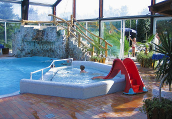 Espace piscine intérieure au Type C House 363 364 361 362 en Allemagne, avec toboggan et cascade de pierre.