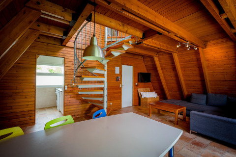 Interieur van een gezellige houten lodge met wenteltrap, moderne woonkamer en open keukenruimte