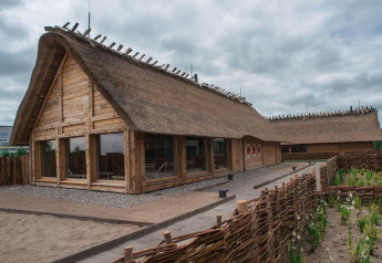 Lodge tradizionale con tetto di paglia e struttura in legno, vista esterna, Nurdachhaus 65 mq, Germania.