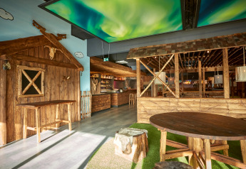 Gemütliche Lodge mit Holzmöbeln, rustikaler Einrichtung und einer Decke mit Nordlichtprojektion.