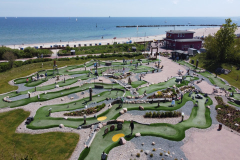 Mini-golf course by the beach at Nurdachhaus Saver rate 65 sqm in Germany, with sea view and people.