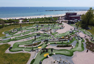 Mini-golfbane ved stranden nær Nurdachhaus Saver rate 65 sqm, Tyskland, med havudsigt og folk.