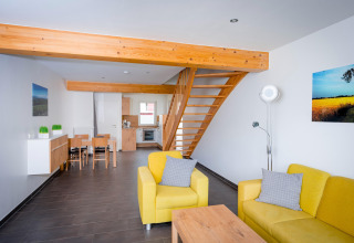 Moderne woonkamer in Ostseeresort Dampland-Terrace house HiPr met gele banken, trap en open keuken.