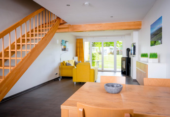 Soggiorno luminoso e moderno presso Ostseeresort Dampland-Terrace House con scale in legno e divani gialli.