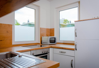Moderne keuken met witte kasten, houten werkblad en magnetron in Ostseeresort Dampland-Terrace house HiPr.