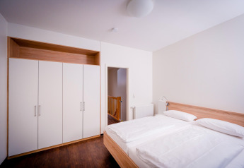 Moderne slaapkamer in Ostseeresort Dampland-Terrace house HiPr, Duitsland, met dubbel bed en kleerkast.