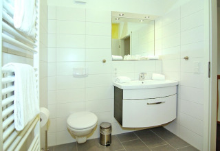 Moderne badkamer in Ostseeresort Dampland-Terrace house HiPr in Duitsland met toilet en wastafel.