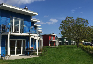 Række af farverige terrassehuse på Ostseeresort Dampland i Tyskland med grønne og blå nuancer.