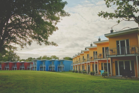 Kleurrijke terraswoningen bij Ostseeresort Dampland in Duitsland, omgeven door grasveld en bomen.