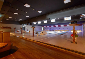 Foto einer modernen Bowlingbahn in einer Lodge mit mehreren Bahnen, Sitzbereichen und Bowlingkugeln.