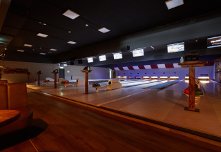 Billedet viser en moderne bowlingbane i en lodge med flere baner, kugler og afslappede siddeområder.