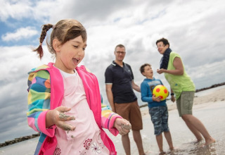 Blije familie speelt op het strand bij Ostseeresort Dampland-Terrace house HiPr, Duitsland, op een bewolkte dag.