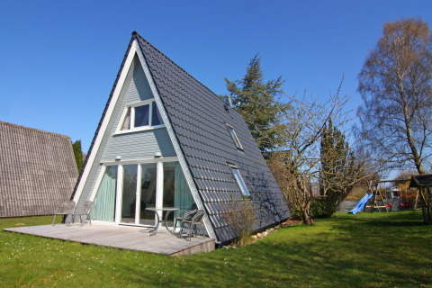 Casa de vacaciones tipo A con terraza y jardín bajo un cielo azul, ubicada en Alemania.