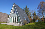 A-vormig vakantiehuis met terras en tuin onder een blauwe lucht, gelegen in Duitsland.
