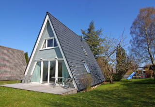 Casa vacanze a forma di A con terrazza e giardino sotto un cielo blu, situata in Germania.