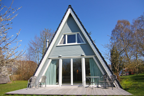 Maison de vacances en forme de A avec terrasse, mobilier de jardin et grandes baies vitrées à Damp, Allemagne.