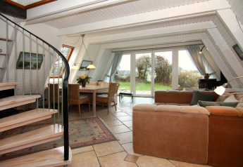 Salon lumineux et moderne du Holiday home «Damp 90 sqm 5 Persons» en Allemagne, avec vue sur jardin et escalier en colimaçon.