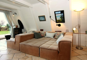 Living room with large beige sofa, bright walls, and garden view at Holiday home Damp, Germany, cozy setup.