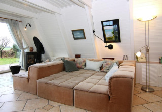 Living room with large beige sofa, bright walls, and garden view at Holiday home Damp, Germany, cozy setup.