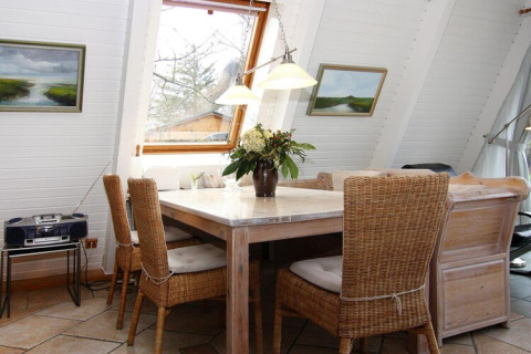 Coin repas lumineux du gîte 'Damp 90 m² 5 personnes' en Allemagne, avec chaises en osier et grande fenêtre.