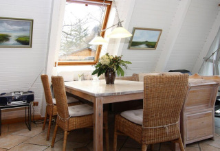 Luminoso comedor en la casa vacacional 'Damp 90 sqm 5 Persons' en Alemania, con sillas de mimbre y ventana grande.