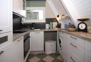 Moderne compacte keuken in vakantiehuis «Damp 90 sqm 5 Persons» in Duitsland met elektrische apparaten.
