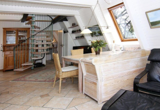 Lichte en ruime leefruimte in vakantiewoning Damp 90 sqm 5 Personen in Duitsland met draaitrap en eetgedeelte.