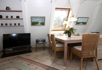 Woonkamer in Holiday home «Damp 90 sqm 5 Persons» in Duitsland met eettafel, tv en groot raam.