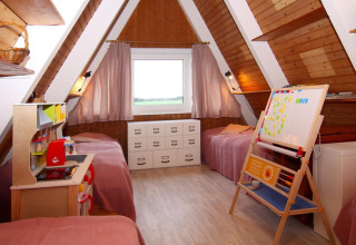 Kinderzimmer im Holzstil mit zwei Einzelbetten, Spielküche und Tafel in einem gemütlichen A-Frame-Ferienhaus.