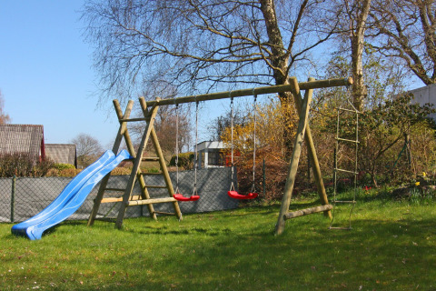 Area giochi con scivolo, altalene e scala di corda nel giardino di Holiday home «Damp 90 sqm 5 Persons» in Germania.