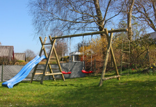 Parque infantil con tobogán, columpios y escalera de cuerda en el jardín de Holiday home 'Damp 90 sqm 5 Persons', Alemania.