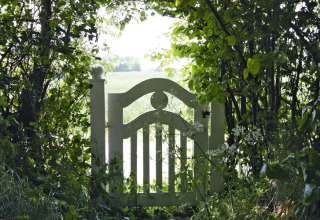 Portail de jardin blanc entouré de verdure au Holiday home Damp 90 sqm 5 Persons en Allemagne.