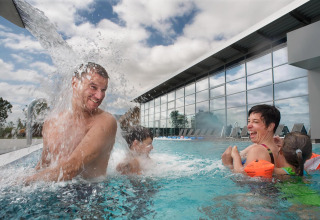 Family enjoys playful moments in an outdoor pool at Nurdachhaus Regular rate 85 sqm lodge in Germany.
