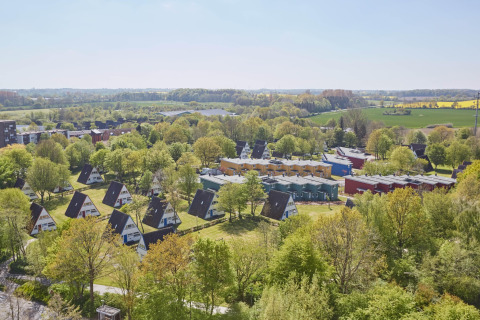 Aerial view of Nurdachhaus HiPr 85 sqm lodge in Germany, surrounded by green trees and open countryside.
