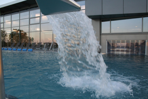 Outdoor swimming pool with waterfall feature at Nurdachhaus HiPr 85 sqm lodge, located in Germany.