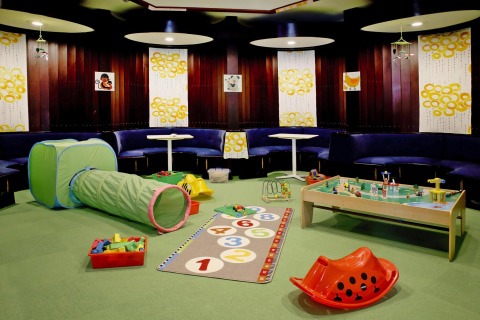 Speelkamer voor kinderen in een lodge met speeltunnel, speelkleed, bouwstenen en ronde zitbanken.