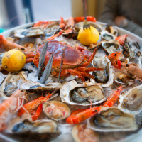 Bandeja abundante de mariscos frescos con camarones, cangrejo, ostras y limón sobre hielo en parque vacacional.