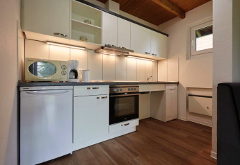 Moderne Küche in einer Lodge mit weißen Schränken, Backofen, Geschirrspüler und Holzboden.