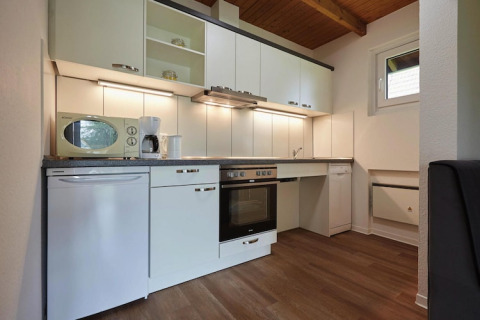 Moderne keuken in een lodge met witte kasten, oven, vaatwasser, microgolf en houten vloer.