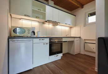 Moderne keuken in een lodge met witte kasten, oven, vaatwasser, microgolf en houten vloer.